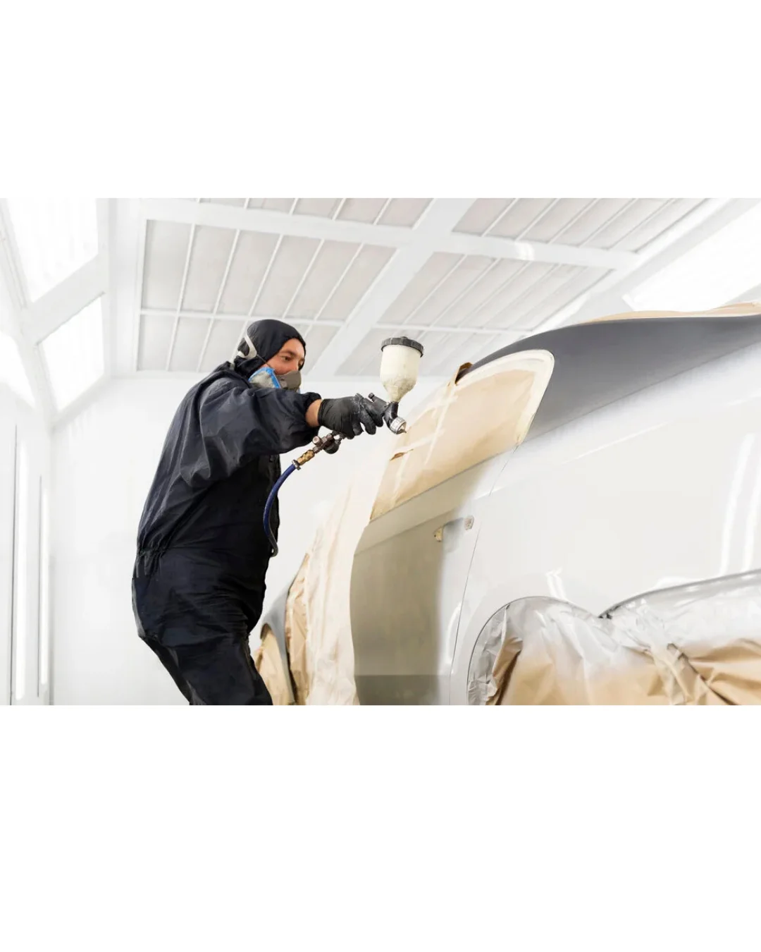 Profissional pintando um veículo em cabine de pintura